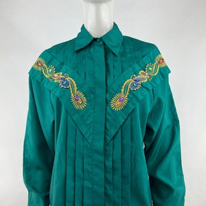 May include: A green long-sleeved button-up shirt with a pleated front and colorful jeweled embroidery on the shoulders.