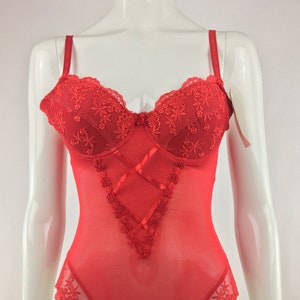 May include: Red lace bodysuit with a sheer mesh fabric and floral embroidery. The bodysuit has adjustable straps and a V-neckline.