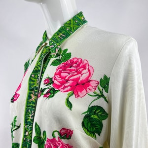 May include: A white button-up shirt with a green and white floral print. The shirt has a collar and long sleeves.