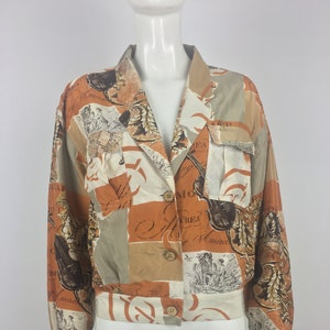 Puede incluir: Una chaqueta de botones con estampado marrón y beige, con cuello blanco y mangas largas. La chaqueta tiene un diseño de patchwork con notas musicales e instrumentos impresos.