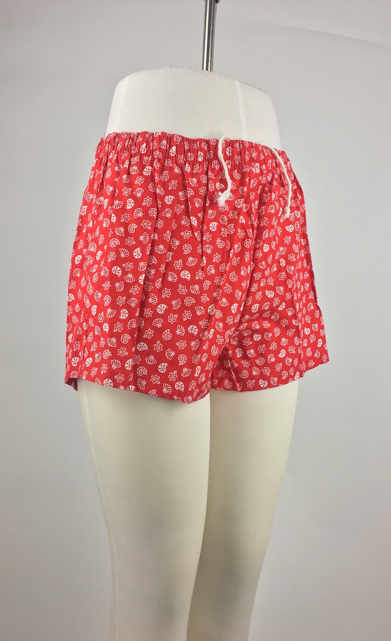 May include: Red shorts with a white seashell pattern.