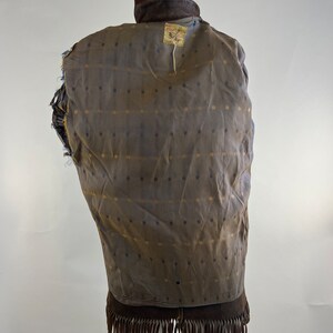 May include: Brown suede jacket with fringe on the bottom. The jacket has a brown and gold patterned lining. The label on the back reads "Ray Price Furs".