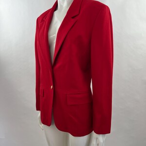 May include: A vibrant red blazer with a classic design. The blazer features a notched lapel, a single-button closure, and a front pocket. The long sleeves and tailored fit create a polished look. The blazer is displayed on a mannequin.