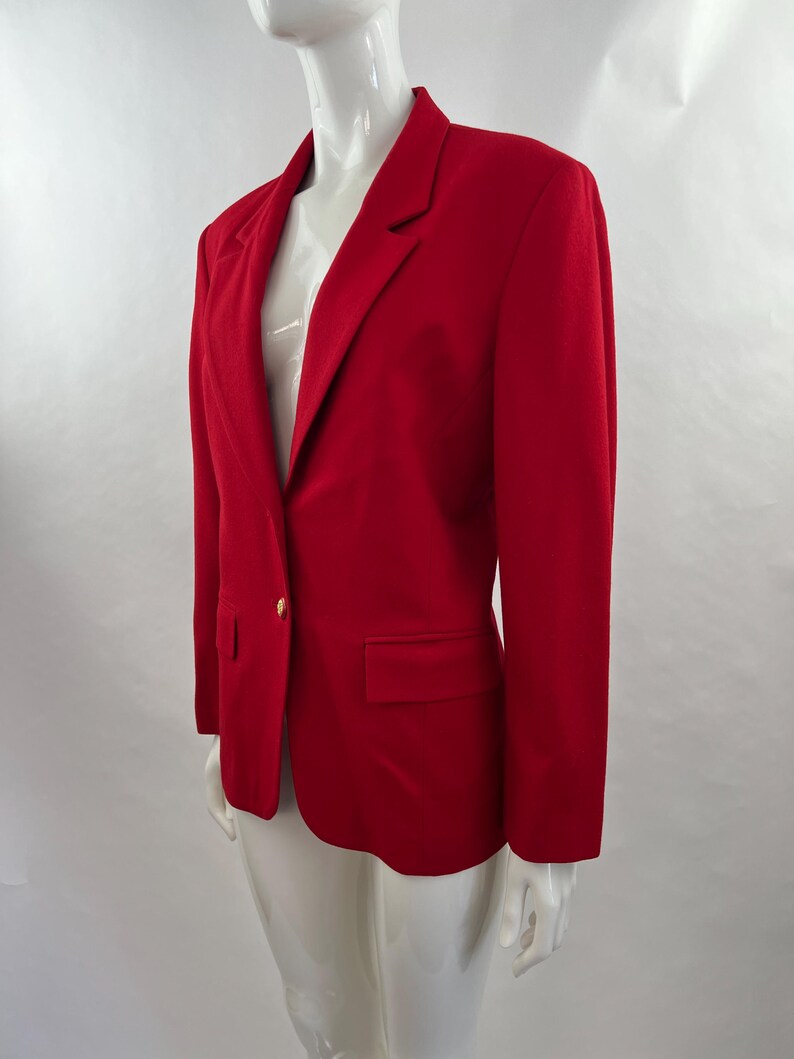 May include: A vibrant red blazer with a classic design. The blazer features a notched lapel, a single-button closure, and a front pocket. The long sleeves and tailored fit create a polished look. The blazer is displayed on a mannequin.