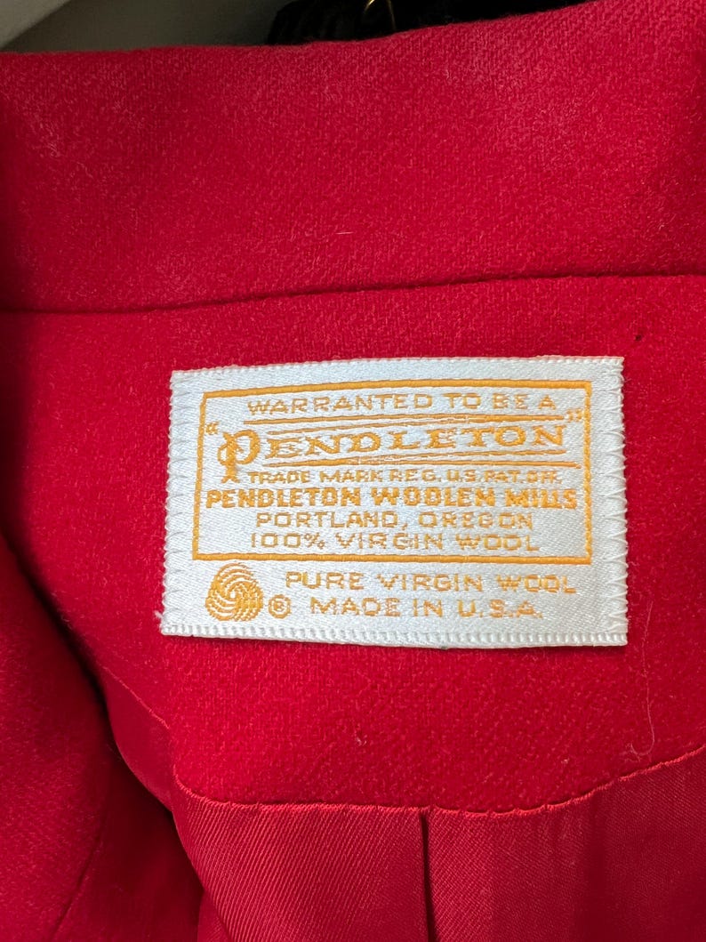 May include: Close-up of a bright red garment with a white label. The label reads "PENDLETON WOOLEN MILLS, PORTLAND, OREGON, 100% VIRGIN WOOL, PURE VIRGIN WOOL, MADE IN U.S.A."