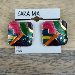 May include: A pair of square-shaped earrings with a geometric design. The earrings are made of metal and have a multi-colored enamel finish. The colors include pink, green, blue, yellow, orange, and purple. The earrings are marked "CARA MIA" and "STEEL POSTS".