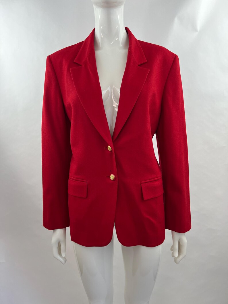 May include: A vibrant red blazer with a classic design. The blazer features a notched lapel, two front pockets, and gold-colored buttons. The tailored fit and bold color make it a statement piece.