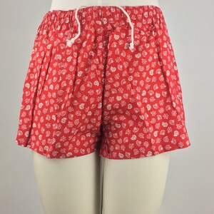 May include: Red shorts with a white seashell pattern.