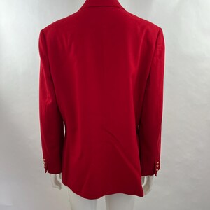 May include: A vibrant red blazer with gold-colored buttons on the sleeves. The back view of the blazer shows a classic tailored design. The blazer is displayed on a mannequin.