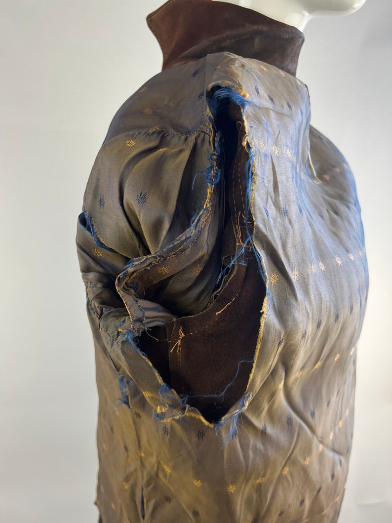 May include: A brown suede jacket with a gold and black patterned lining. The lining is torn in the shoulder area.