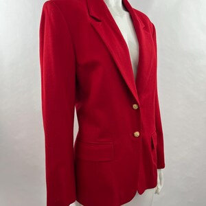 May include: A vibrant red blazer with a classic design. The blazer features a notched lapel, a single-button closure with two gold-colored buttons, and a front pocket. The tailored fit and bold color make it a statement piece.