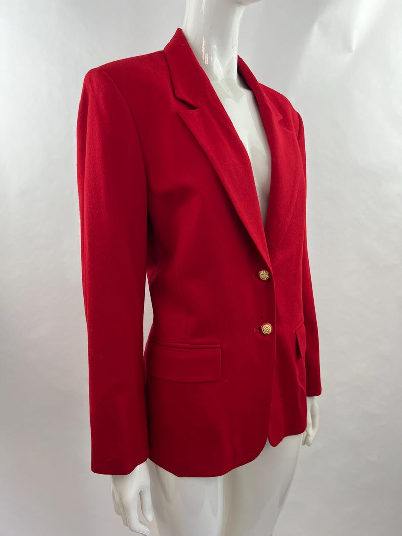 May include: A vibrant red blazer with a classic design. The blazer features a notched lapel, a single-button closure with two gold-colored buttons, and a front pocket. The tailored fit and bold color make it a statement piece.