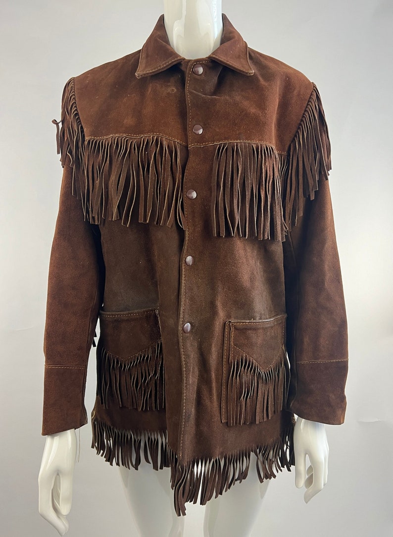 May include: A brown suede jacket with fringe detailing. The jacket has a button-up front and two flap pockets.