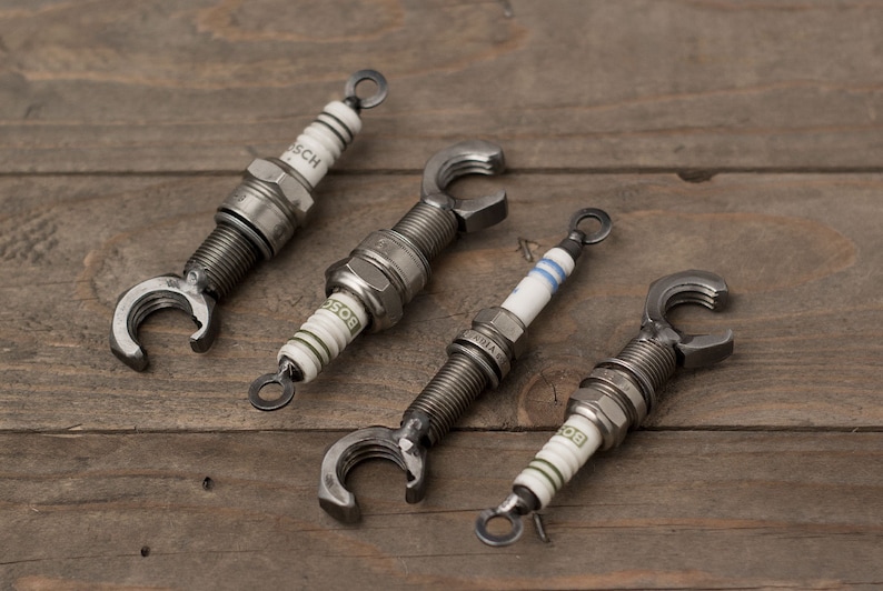 May include: Four spark plugs with metal bottle openers attached to the end. The spark plugs are silver and have the word "BOSCH" printed on them.