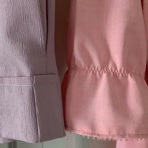 Puede incluir: Dos muestras de tela, una lavanda y otra rosa, con un borde fruncido en la muestra rosa.