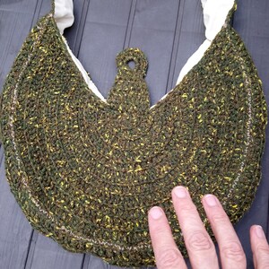 May include: A green and yellow crocheted bag with a white lining and a brown leather handle.