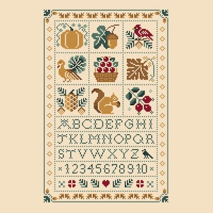 May include: A cross-stitch sampler pattern on a cream background featuring a grid of autumn-themed icons including a pumpkin, turkey, squirrel, and cardinal. Below the icons are the alphabet from A to Z and numbers 0 through 9 in a dark font.