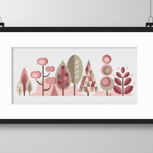 May include: A framed cross-stitch pattern featuring a row of stylized trees in shades of pink, brown, and beige. The trees are geometric in shape and have a whimsical, modern feel.