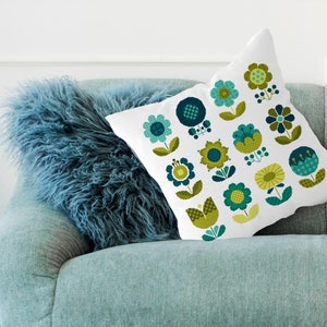 May include: A white cushion with a pattern of green and blue flowers. The cushion is sitting on a blue sofa.