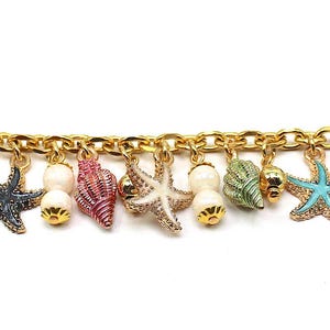 K&ouml;nnte beinhalten: Ein goldenes Kettenarmband mit mehreren Anh&auml;ngern, darunter Muscheln, Seesterne und Perlen. Die Anh&auml;nger sind in verschiedenen Farben, darunter rosa, blau, gr&uuml;n und wei&szlig;.