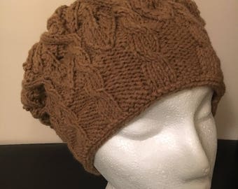 Puede incluir: Un gorro de punto marrón con un patrón de punto de cable.