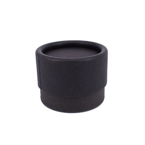 May include: A black round cardboard box with a textured surface.