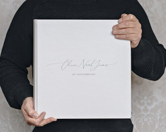 May include: White photo album with the text "Oliver Noah James" and "28th September 2021" in black script.