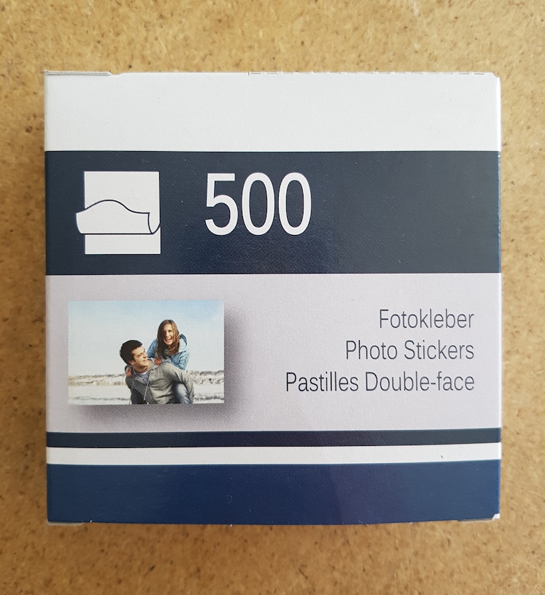 May include: A box of 500 double-sided photo stickers. The box is blue and white with a picture of a couple on the front. The text on the box reads "Fotokleber Photo Stickers Pastilles Double-face".