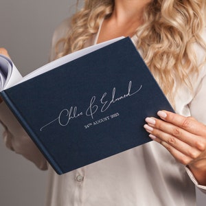 May include: A navy blue wedding guest book with the names "Chloe & Edward" and the date "24th August 2023" printed in silver script.