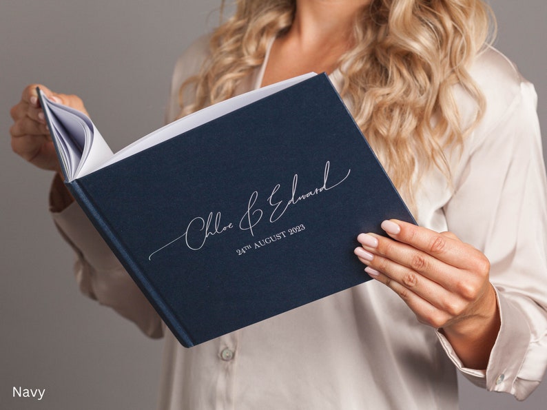 May include: A navy blue wedding guest book with the names "Chloe & Edward" and the date "24th August 2023" printed in silver script.