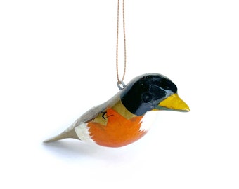 May include: A wooden bird ornament painted in shades of black, orange, white, and yellow. The bird is hanging from a brown string.