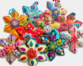 Könnte beinhalten: Eine Sammlung von zehn Filz-Schneeflocken-Anhängern in verschiedenen Farben, darunter Rot, Gelb, Blau, Grün und Lila. Jede Schneeflocke hat aufwendige Stickdetails.