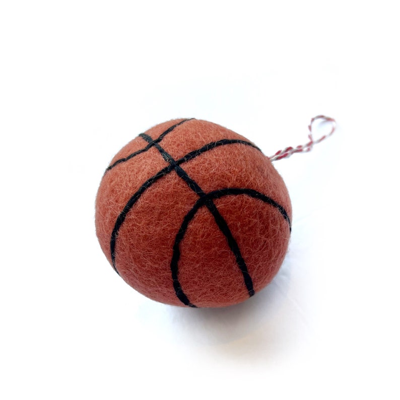 May include: A felt basketball ornament with black stitching and a red and white string for hanging.