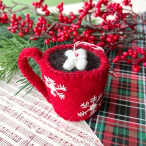 Handmade Hot Chocolate Christmas ornament made of red felt styled with Christmas greens and berries
