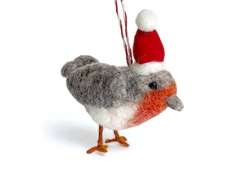 May include: A gray and white felt robin wearing a red Santa hat with a white pom-pom. The robin is a Christmas ornament with a red string for hanging.