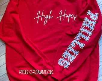 May include: Red crewneck sweatshirt with white text that says "High Hopes" and a blue and white "PHILLIES" graphic on the sleeve.