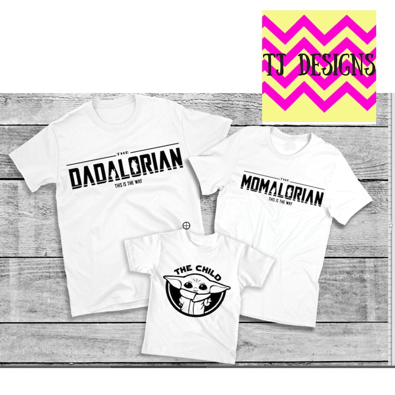 May include: Three white t-shirts with black text. The largest shirt reads "THE DADALORIAN" and "THIS IS THE WAY". The second shirt says "THE MOMALORIAN" and "THIS IS THE WAY". The smallest shirt says "THE CHILD" with a graphic.