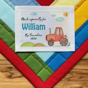 May include: A white fabric label with a red tractor illustration and the text "Made especially for William By Grandma 2022".