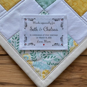 May include: White fabric label with black text and red hearts. The text reads "Made especially for Seth & Chelsea In celebration of their marriage on March 15, 2021 Love, Mom"