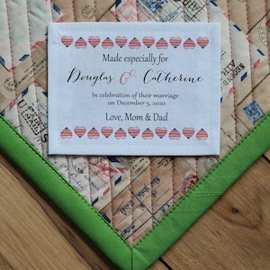 Puede incluir: Una etiqueta de tela blanca con corazones rojos y el texto "Made especially for Douglas & Catherine In celebration of their marriage on December 5, 2020 Love, Mom & Dad"