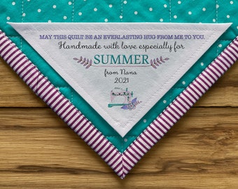 Może przedstawiać: Biała trójkątna etykieta do koca z tekstem "MAY THIS QUILT BE AN EVERLASTING HUG FROM ME TO YOU. Handmade with love especially for SUMMER from Nana 2021".