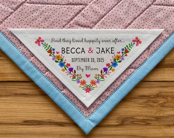 Könnte beinhalten: Ein weißes Stoffdreieck mit floralem Rand und dem Text "And they lived happily ever after... Becca & Jake September 20, 2025 By Mom".