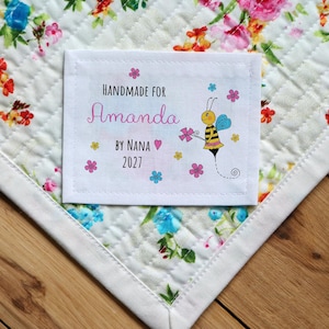 May include: A white fabric label with a bee illustration and the text "Handmade for Amanda by Nana 2027".