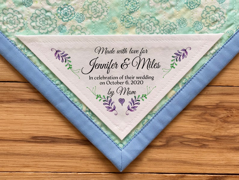 May include: A white triangular fabric label with a floral design and the text "Made with love for Jennifer & Miles In celebration of their wedding on October 6, 2020 by Mom".