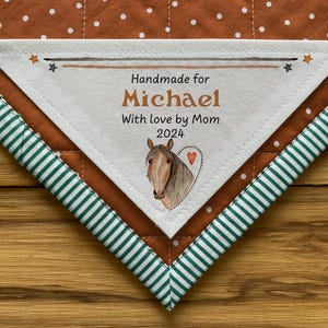 May include: A white fabric label with brown stitching, featuring the text "Handmade for Michael With love by Mom 2024" and a watercolour illustration of a brown horse with a pink heart.
