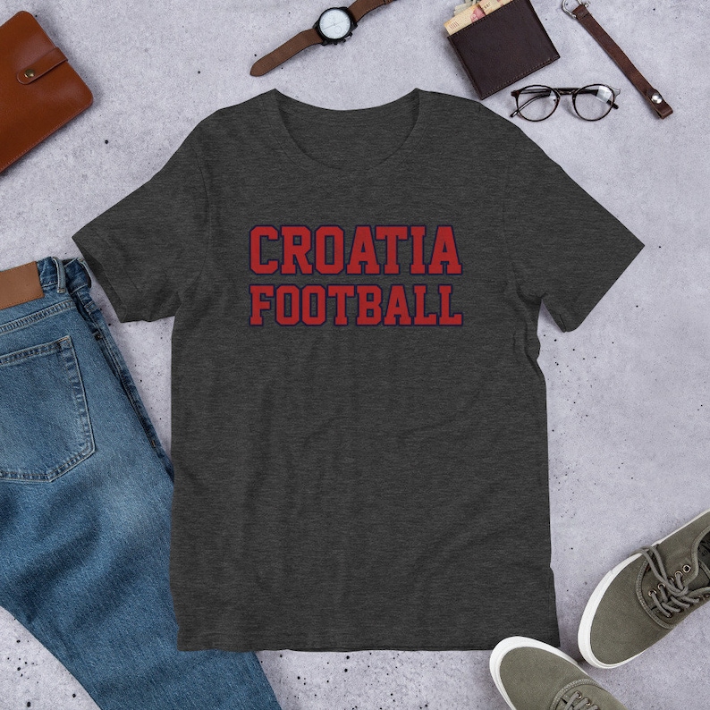 May include: Dark heather grey t-shirt with red text that says "CROATIA FOOTBALL" in a collegiate font.