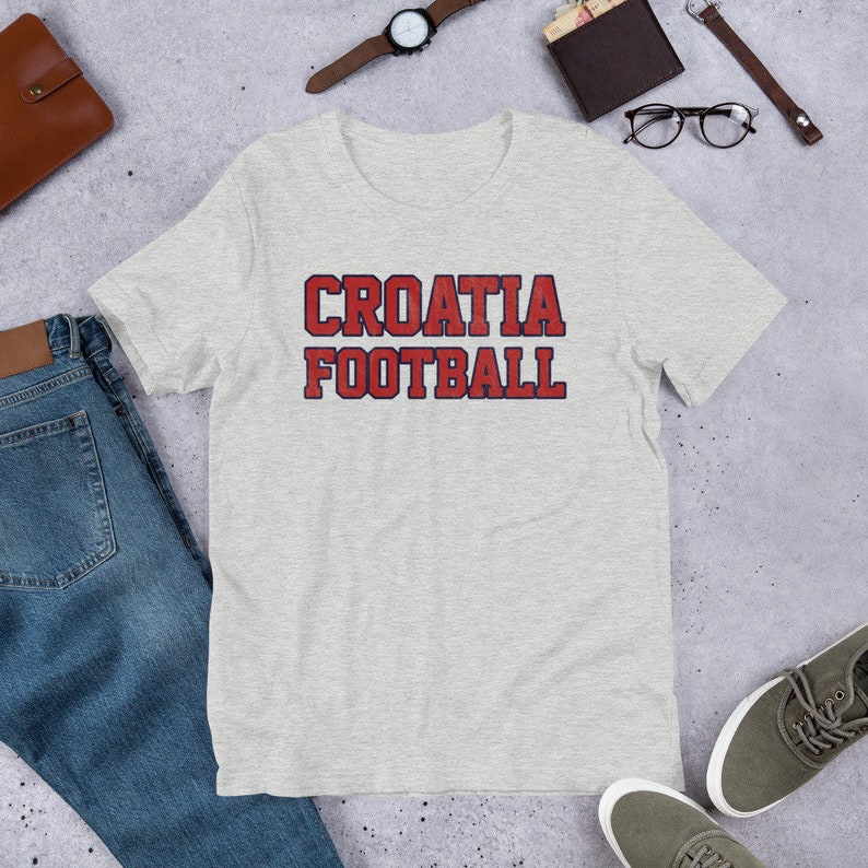May include: A heather grey t-shirt with the text "CROATIA FOOTBALL" in red with a blue outline.