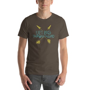 May include: A brown t-shirt with a graphic of two crossed arrows and the text "Lift Big Throw Hard" in blue and yellow.