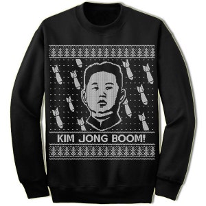 May include: Black Christmas sweater with a white knit design. The sweater features a portrait of Kim Jong-un and the text "Kim Jong Boom!"