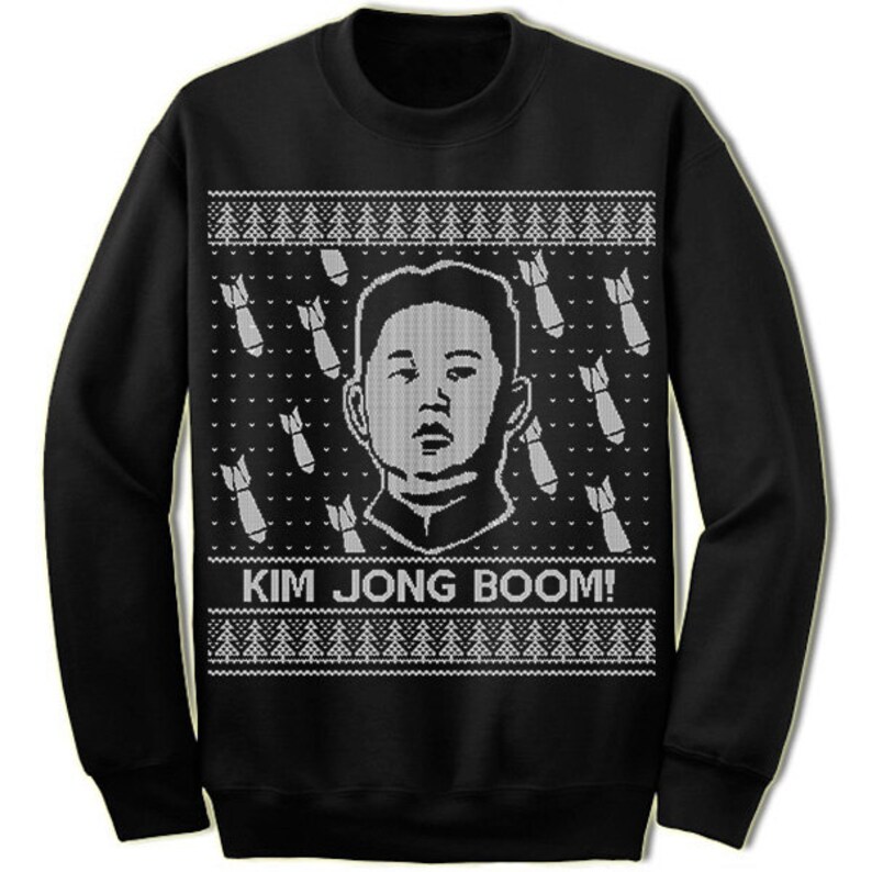May include: Black Christmas sweater with a white knit design. The sweater features a portrait of Kim Jong-un and the text "Kim Jong Boom!"